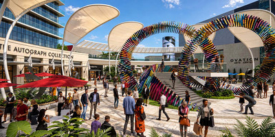 A project rendering showing sculptures, buildings, and crowds at midday.